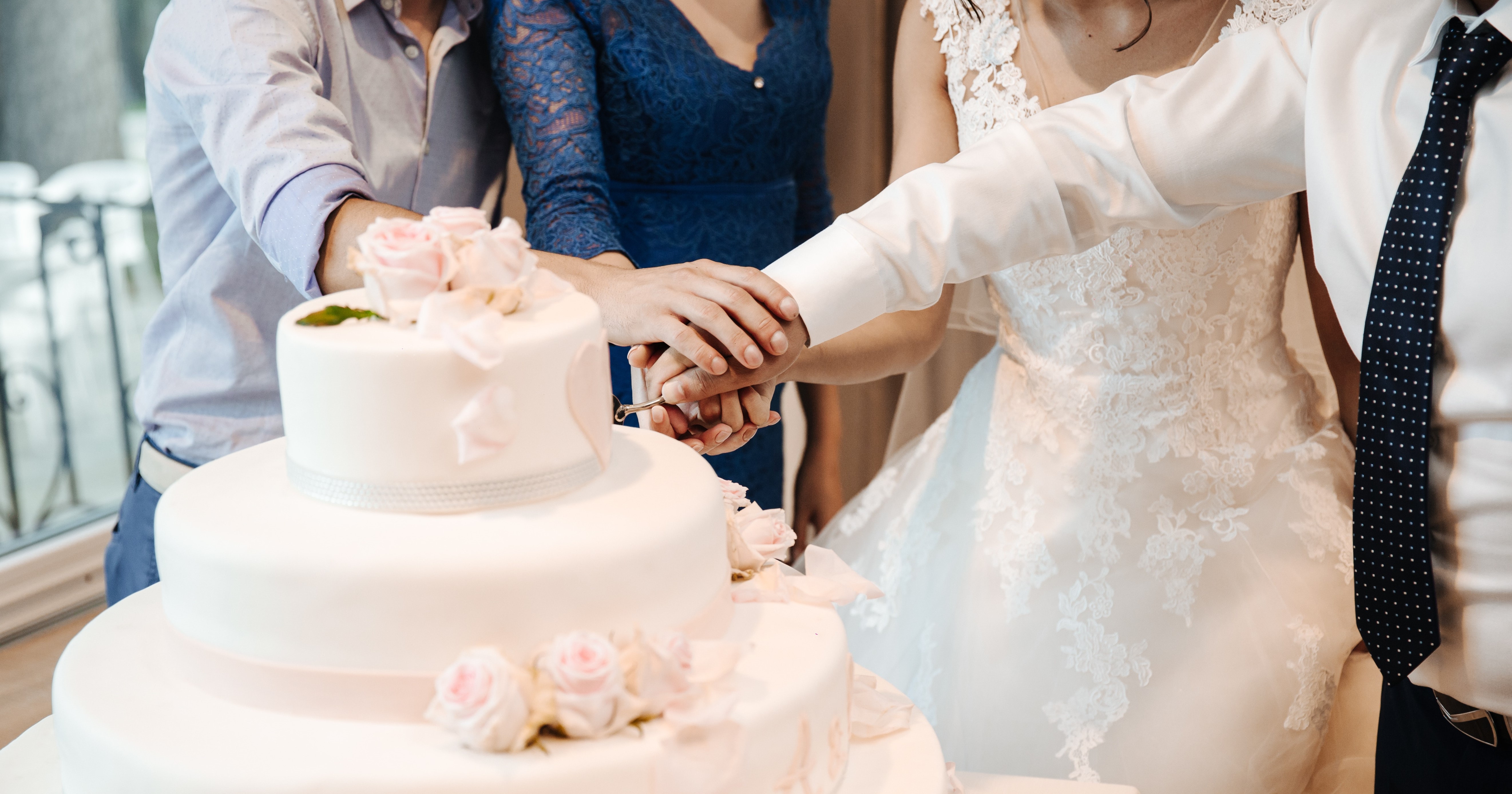 Bride, groom, and family cutting a wedding cake